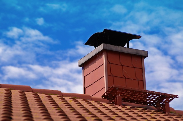 Stock photo of unique chimney cap on tile roof and beautiful blue and cloudy sky in the background.  We also do dampers.