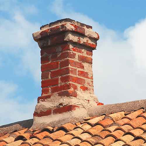 Stock photo of Crown that needs repair.  Spalling on the top looks like a messing tuckpointing job that needs to be redone. The roof is made of tile and the sky is a beautiful blue with clouds.