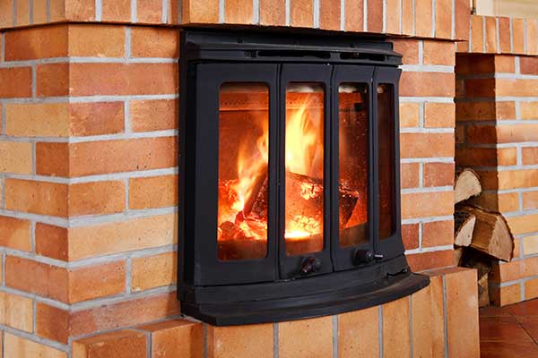 Wood Burning Inserts Wood burning stove insert is beautifully rounded on the front and has double doors. The surround is all brick with a tall space to the right that hold wood.