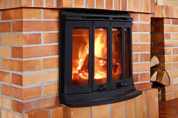 Wood burning stove insert is beautifully rounded on the front and has double doors.  The surround is all brick with a tall space to the right that hold wood.